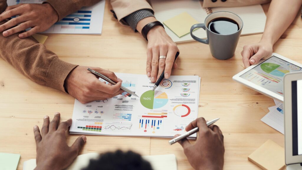 Fundos Imobiliários Mais Rentáveis
Profissionais de negócios discutindo gráficos e dados financeiros sobre investimentos imobiliários em um escritório moderno com vista para a cidade.